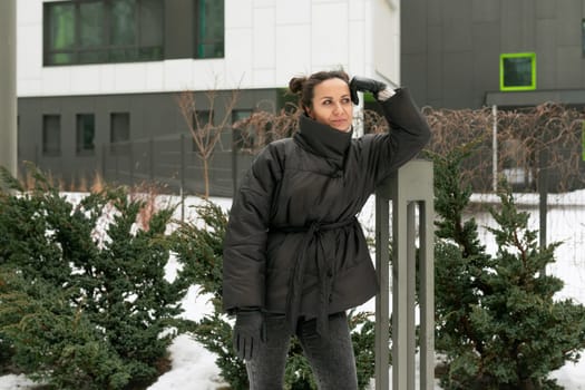 A young pretty woman in a winter jacket with a bun hairstyle walks around the city.