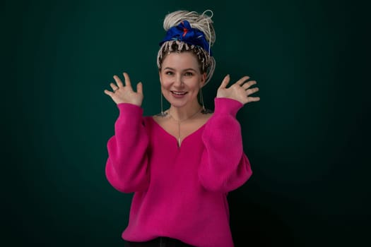 A woman is pictured wearing a pink sweater with a blue bow in her hair. She looks directly at the camera, standing in a casual pose.