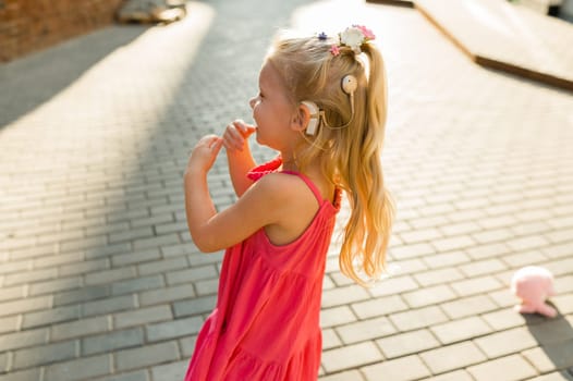 Funny baby with cochlear implant walks outdoor. Hearing aid and medicine innovating technology concept. Diversity and inclusion. Copy space.