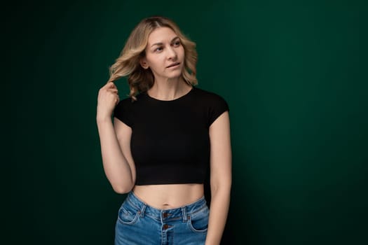 A young woman wearing a black crop top strikes a pose for a photograph, showcasing confidence and style. Her body language exudes self-assuredness as she flaunts her outfit.