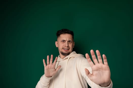 A man wearing a hoodie is standing with his hands raised in the air. He appears to be holding them up voluntarily, with no signs of aggression or threat.