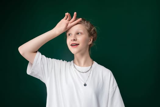 A woman in a white shirt strikes a pose as someone takes a photograph. She stands confidently, with a slight smile on her face, against a neutral backdrop. The womans body language suggests she is comfortable in front of the camera.