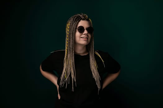 A woman with long dreadlocks is standing in front of a vibrant green background. She exudes confidence and independence as she poses for the camera.