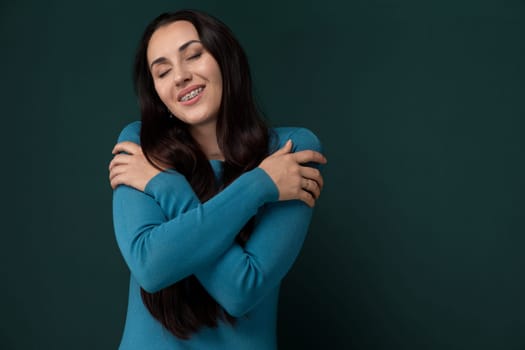 A woman with brown hair and a white blouse stands with her arms crossed, smiling. She exudes confidence and positivity in a casual setting.