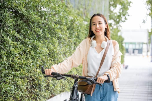 Lifestyle Asian young woman walking alongside with bicycle on summer in countryside outdoor, Happy female smiling walk down the street with her bike on city road, ECO environment, healthy travel