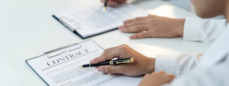 Business executive signing contract agreement document on the bale with the help from company attorney or lawyer service in law firm office. Business investing and finalizing legal processing. Shrewd