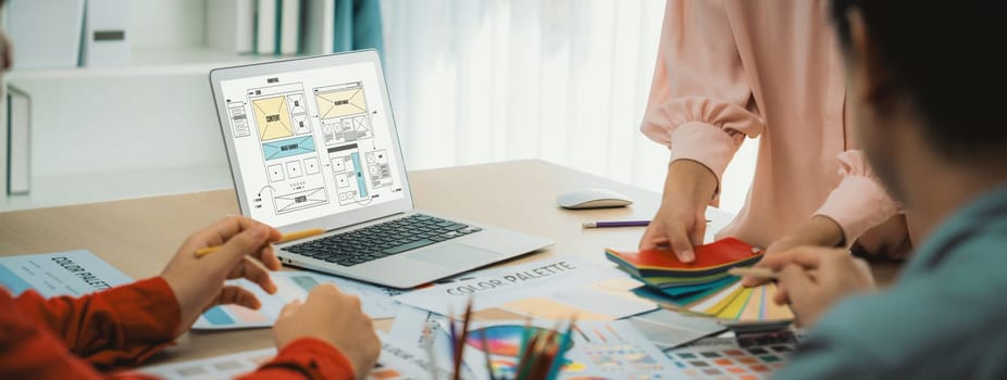 Cropped image of interior designer team discuss the material color while laptop displayed website wireframe designs for mobiles app and website. Creative design and business concept. Variegated.