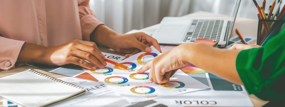 Cropped image of professional interior designers discuss and brainstorm main theme color in project on meeting table with color palette scatter around. Creative interior design concept. Variegated.