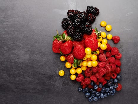 Group, above and fruit by dark background for fresh, smoothie and vegan diet on table with strawberry. Blueberry, blackberry and detox with protein on grey surface for cocktail, milkshake and energy.