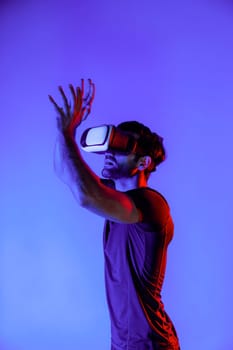 Caucasian man playing basketball while wearing VR headset to enter metaverse or simulated world with neon light. Sport gamer play sport or exercise while standing at virtual reality world. Deviation.