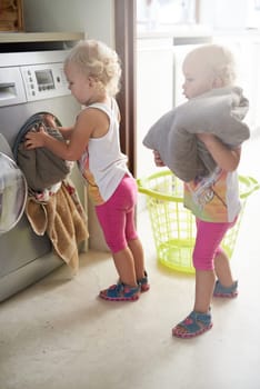 Kids, washing machine and siblings with laundry in house for learning, playing or fun bonding together. Cleaning, games and children help with towels at home for child development, housework or chore.