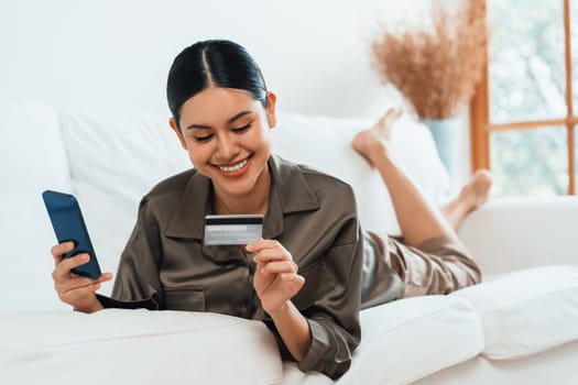 Young happy Asian woman buy product by online shopping at home while ordering items from the internet with credit card online payment protected by uttermost cyber security from online store platform