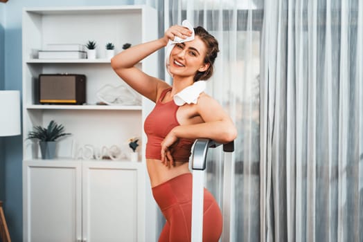 Athletic and sporty woman running on treadmill running machine during home body workout exercise session for fit physique and healthy sport lifestyle at home. Gaiety home exercise workout training.
