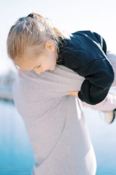 Dad lifts up the little girl holding onto his shoulder. Back view. High quality photo