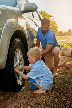 Outdoors, man and child with cleaning car in nature for teamwork, maintenance and childhood development. Dad, boy and kid with washing vehicle on ground for teaching, hygiene and help in parenthood.