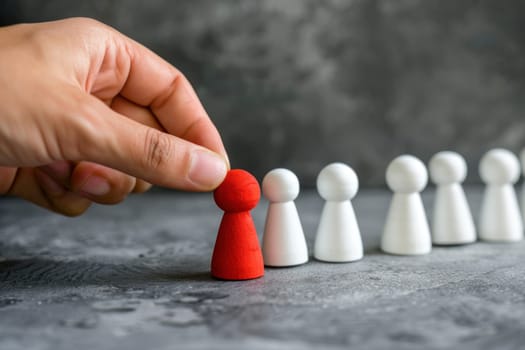 A hand is holding a red piece of wood that is on top of a line of white pieces.