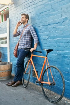 Bike, phone call and smile with business man on blue wall in city for morning commute to work. Contact, thinking and transportation with happy young employee talking on mobile for communication.