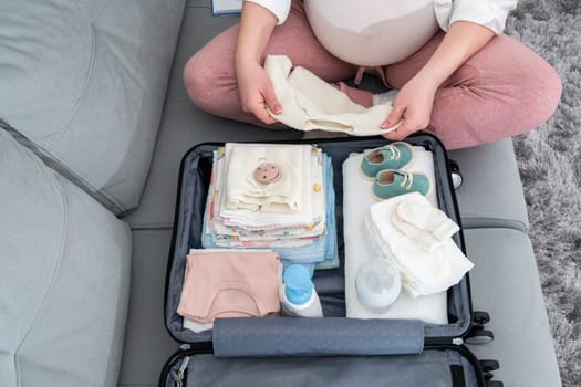 Top view of a pregnant woman packing a set of necessary things in the maternity hospital.