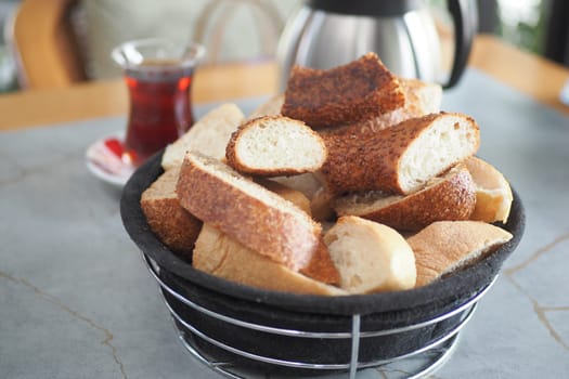 bread rolls rest in a black bowl on the table.