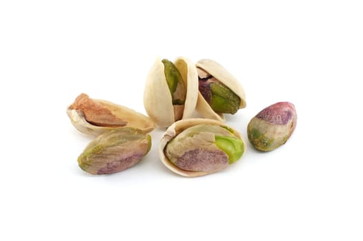 Pistachios are randomly spread across the white surface, some pistachios being in-shell and others peeled exposing the green nuts inside