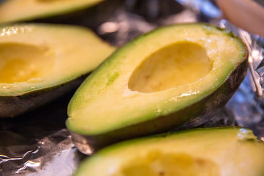 Sliced half of an avocado on aluminum foil