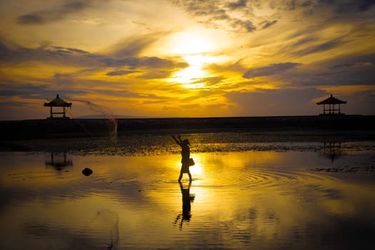 Traditional Fisherman at Sunrise in Bali between two pavilions