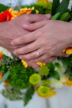 Bride and Groom Hands on Bouquet during a summer wedding