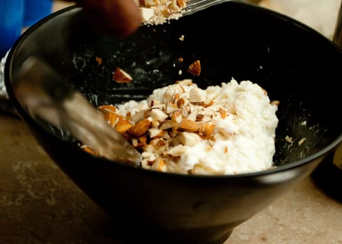 pouring crushed almonds into ricotta