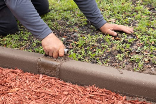 Worker shaping cement for a garden border