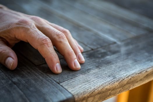 Mans hand resting on a wooden table