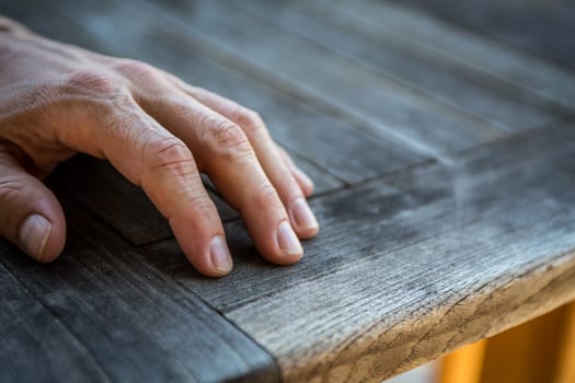 Mans hand resting on a wooden table