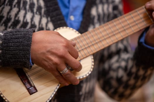 Peruvian Playing a Miniature Guitar as a demonstration