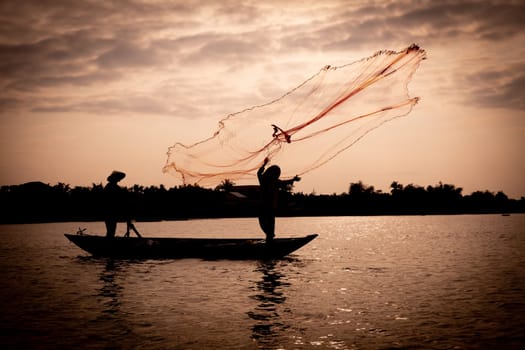 Vietnamese fisherman throwing a net to catch food for the village