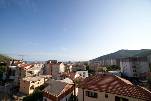 Red roofs of apartment buildings at the foot of the mountains near the sea. Budva, Montenegro. High quality photo