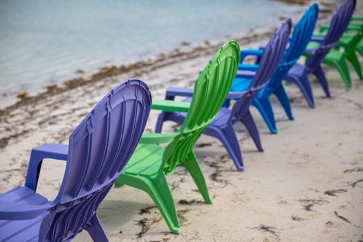 Purple, green and blue lounge chairs on the beach
