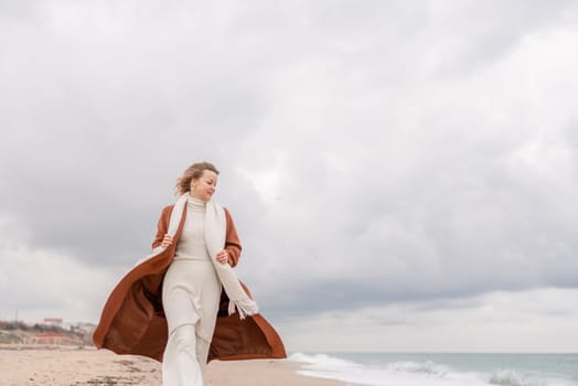 Blond woman Christmas sea. Christmas portrait of a happy woman walking along the beach and holding a Christmas tree on her shoulder. She is wearing a brown coat and a white suit