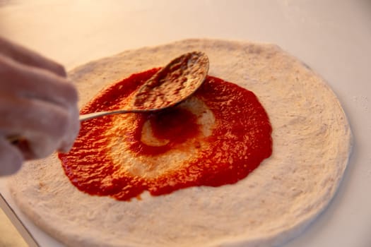 Spreading Marinara on a Pizza before adding cheese