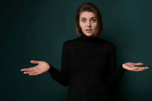 A woman dressed in a black shirt is extending her hands outward. Both of her hands are open, palms facing upward. She appears to be standing with a neutral expression, looking directly ahead.