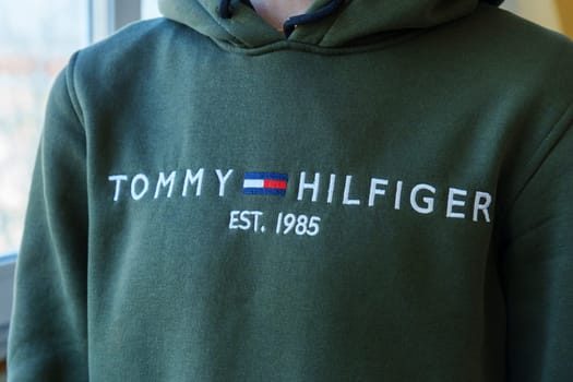 Tyumen, Russia-January 11, 2024: Person in Green Tommy Hilfiger Sweatshirt close up logo. Selective focus