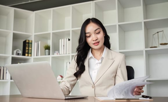 A female Asian lawyer reviews business and real estate laws. Legal consultants provide legal advice and guidance online via laptops in lawyers' offices..