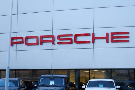 Tyumen, Russia-March 18, 2024: Vehicles parked outside a Porsche dealership, showcasing luxury cars and the iconic Porsche logo.