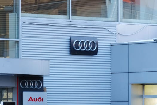 Tyumen, Russia-March 18, 2024: Audi Brand Logo on Gray Textured Wall, close up.