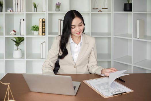 A female Asian lawyer reviews business and real estate laws. Legal consultants provide legal advice and guidance online via laptops in lawyers' offices..