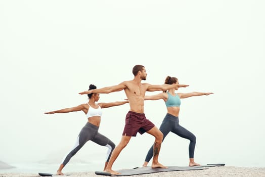 People, stretching and yoga at beach for fitness, exercising and mindfulness or wellness outdoor. Training, friends or man and women with cardio for flexibility, strength and balance or mental health.
