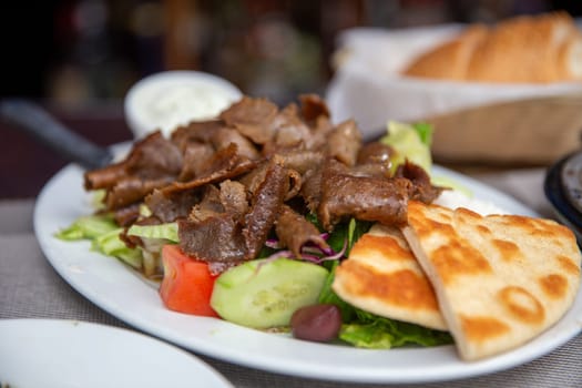 Plated Gyro Platter with salad and yogurt sauce