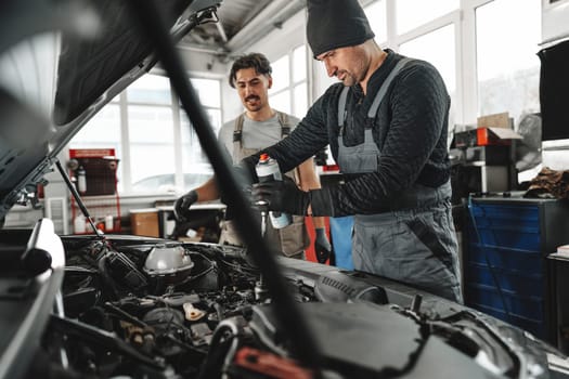 Two male mechanics repairing car in car service close up