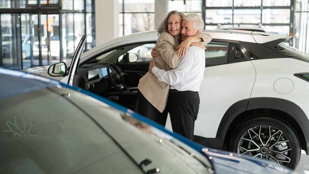Mature Caucasian couple hugging. Elderly man and woman buying a new car