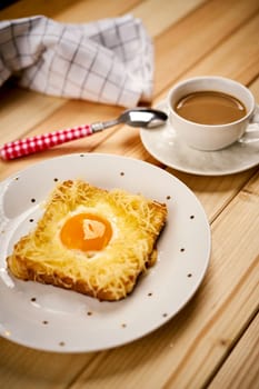 Delicious breakfast set with coffee and toast with fried egg on wooden kitchen table