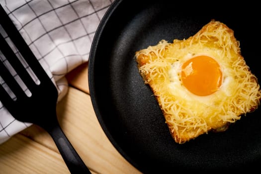 Delicious toast with fried egg and cheese in pan on wooden kitchen table