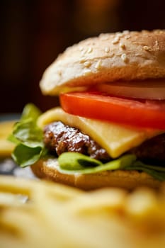 delicious cheeseburger surrounded by french fries on a black table